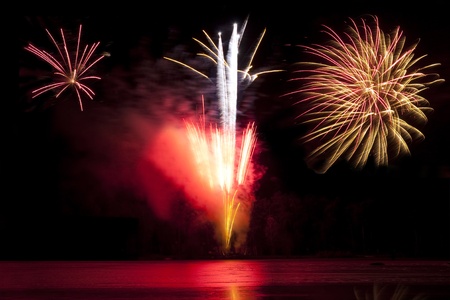 firework display exploding over a lake in winterの写真素材