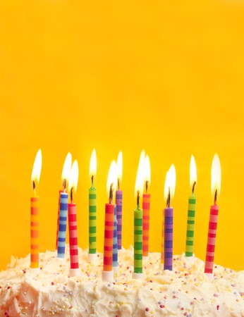 happy birthday cake shot on a yellow background with candles and lots of spaceの写真素材