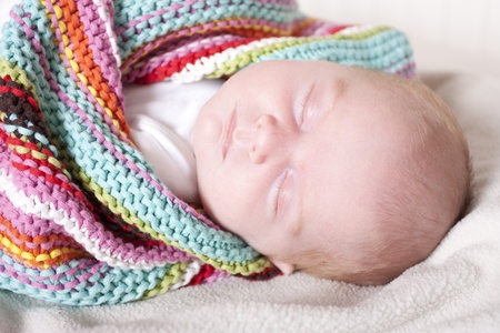 newborn baby girl asleep in wrapped in a striped blanket
