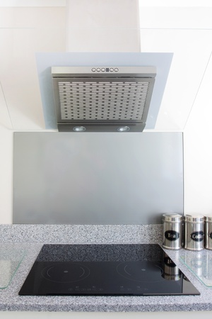 modern kitchen with white units and extrator fan and hobの写真素材