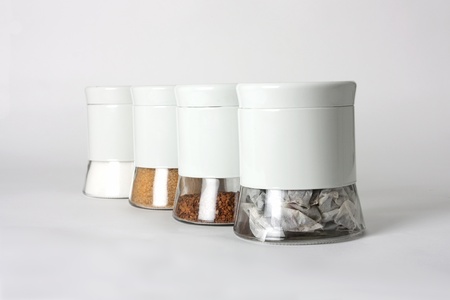 Pots made from glass holding teabags, coffee granules and brown and white sugarの写真素材
