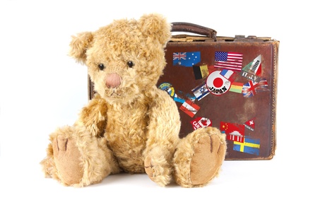 studio shot of a teddy bear and vintage old suitcase with world stickers isolated on a white backgroundの写真素材