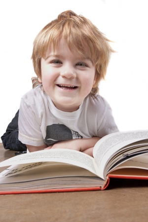 Boy isolated againt a white background reading a book and smilingの写真素材
