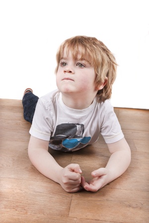 Isolated white wall background of young child latying on the floor thinking looking upの写真素材