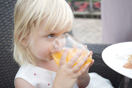 Little girl drinking fresh orange juiceの写真素材