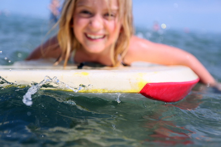 blonde caucasian 7 year old girl bodyboarding, surfing in the sea, north wales, ukの写真素材