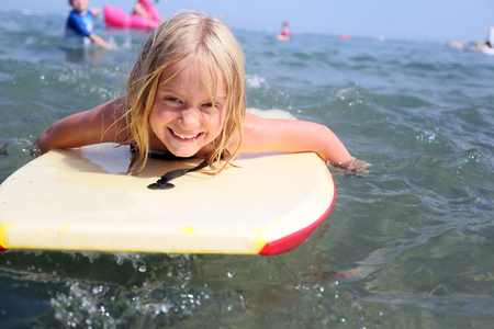 blonde caucasian 7 year old girl bodyboarding in the sea, north wales, ukの写真素材
