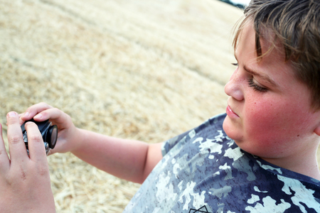 Young boy aged 10 photographing using a sports camera in a corn fieldの写真素材