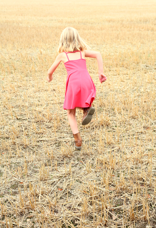 girl wearing pink dress running in a cornfiled in the british countryside, essexの写真素材
