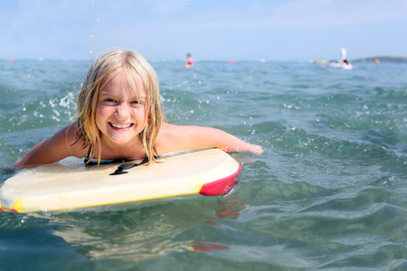 blonde cute girl (age 7) bodyboaring in cornwall or devon in the ukの写真素材