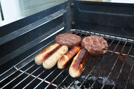 cooking outside on a bbq in the summer charcoal sausages and beefburgersの写真素材