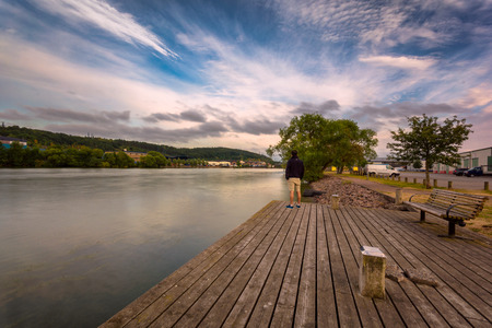 Young adult male vitnessing rising sun in gothenburg Sweden next to river gotaの写真素材