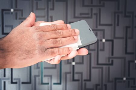 Male cleaning mobile phone with anti bacterial wipes,Sweden
