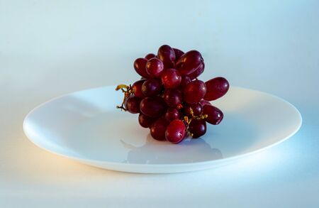 Red grapes  photographed in awhite plate against white background with space for content,Swedenの写真素材
