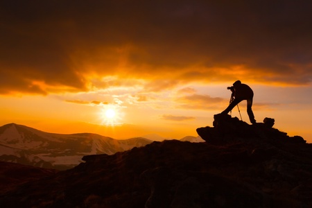 silhouette of a photographer who shoots a sunset in the mountainsの写真素材