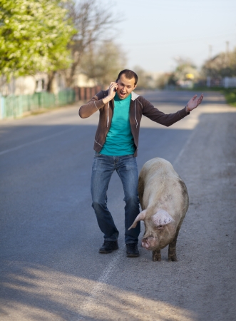 A man with a dirty pig is on the cellphoneの写真素材