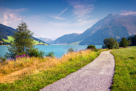 Bicycle path around Resia lake in the Italian Alps. Colorful summer morning on the Reschensee lake. Place is located near the village St. Valentin, Alps, Italy, Europe.の写真素材