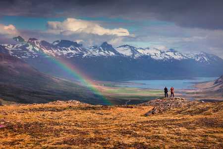Two photographers takes picture in a light rain and rainbow in the Icelandic mountains. Colorful summer morning in the Iceland, Europe. Artistic style post processed photo.の写真素材
