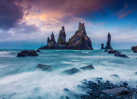 Dramatic seascape of Reynisdrangar cliffs in the Atlantic ocean. Colorful summer sunset in south Iceland, Vic village location, Europe. Artistic style post processed photo.の写真素材
