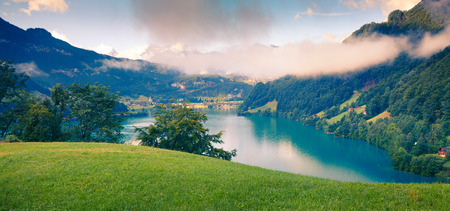 Foggy summer panorama of Lungerersee lake. Colorful morning view of Swiss Alps, Lungern village location, Switzerland, Europe. Green filter toned.の写真素材