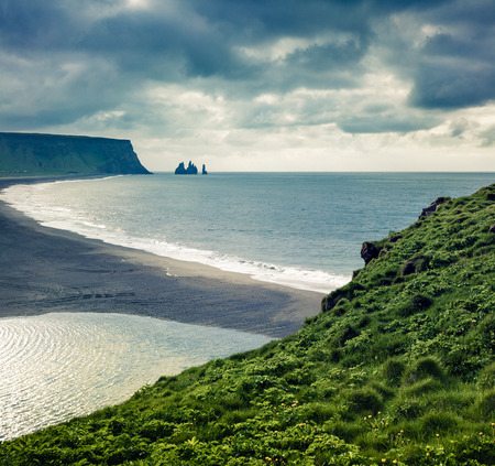 Dramatic summer morning in Dyrholaey Nature Reserve with view of black sund Reynisfjara beach. Great outdoor view of  Reynisdrangar cliffs in the Atlantic ocean, south coast of Iceland, Europe. Green filter toned.の写真素材