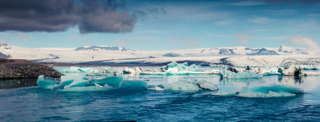 Panorama of floating of blue icebergs in Jokulsarlon glacial lagoon. Dramatic summer morning in...