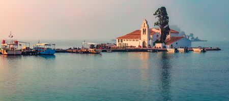 Foggy sunrise of Vlacherna Monastery. Picturesque morning cityscape of Kerkira town, capital of Corfu island, Greece, Europe. Panoramic summer seascape of Ionian Sea. Traveling concept background.の写真素材