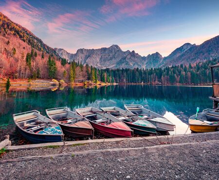 Six pleasure boats on Fusine lake. Dramatic sunset on Julian Alps with Mangart peak on background, Province of Udine, Italy, Europe. Traveling concept background.の写真素材