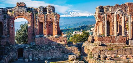 Panoramic morning view of Taormina town and Etna volcano on background. Splendid spring scene of ancient Greco-Roman theater, Sicily, Itale, Europe. Traveling concept background.の写真素材
