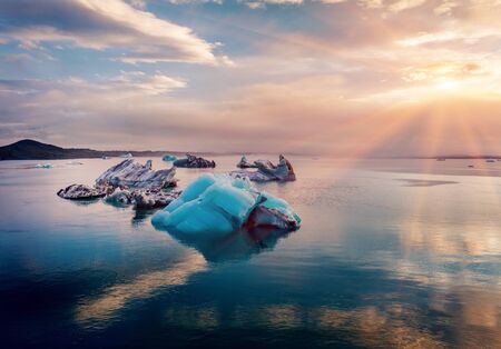 Floating of blue icebergs in Jokulsarlon Glacier Lagoon. Fantastic summer sunset on Vatnajokull National Park. Splendid evening scene of Iceland, Europe. Beauty of nature concept background.の写真素材