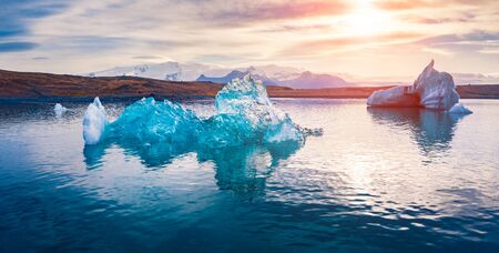 View from flying drone of floating of blue icebergs in Jokulsarlon Glacier Lagoon. Impressive summer sunset in Vatnajokull National Park. Stunning evening scene of Iceland, Europe.の写真素材