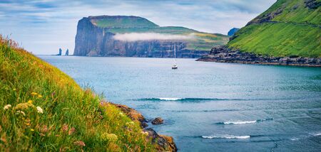 Lonely yacht on the Atlantic coast, Tjornuvik public beach. Stunning morning scene of Streymoy island with Eidiskollur cliffs on background, Faroe Islands, Denmark, Europe. Traveling concept background.の写真素材