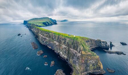 View from flying drone. Gloomy summer scene of Mykines island with old lighthouse. Dramatic morning view of Faroe Islands, Kingdom of Denmark, Europe. Dramatic seascape of Atlantic ocean.の写真素材