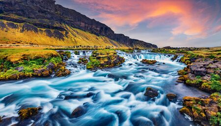 Attractive summer view of small waterfall near Bjodvegur road. Fabulous sunrise on Iceland, Vik location. Beauty of nature concept background.の写真素材