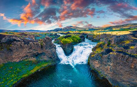 View from flying drone. Dramatic sunset on Hjalparfoss Waterfall. Splendid summer scene of Iceland, Europe. Beauty of nature concept background.の写真素材