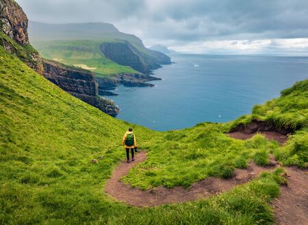 Tourist on trek on Mykines island. Gloomy morning view of Mykines village, Faroe Islands, Denmark, Europe. Fantastic seascape of Atlantic ocean in August. Active tourism concept background.
の写真素材