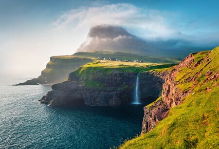 Gorgeous morning scene of Mulafossur Waterfall. Amazinf summer view of Vagar island, Faroe Islands, Denmark, Europe. Beauty of nature concept background.の写真素材