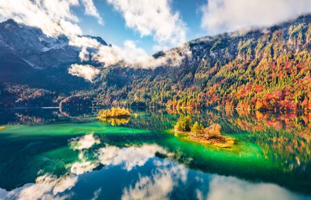 View from flying drone. Misty morning view of Eibsee lake with Zugspitze mountain range on background. Beautifel autumn scene of Bavarian Alps, Germany, Europe. Beauty of nature concept background.の写真素材