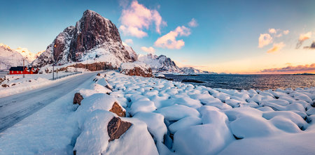 Colorful winter sunrise on Hamnoy village, Lofoten Islands. Fresh snow covered stones on the shore of Norwegian sea. Perfect morning scene of Norway, Europe. Life over polar circle.の写真素材