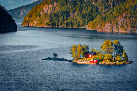 Sramatic summer view with small island with typical Norwegian building with red wall on Lovrafjorden flora, North sea. Spectacular morning view in Norway. beauty of nature concept background.の写真素材
