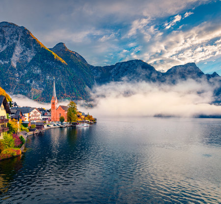 Foggy autumn scene of Hallstatt lake. Incredible morning viev of Hallstatt village, in Austria's mountains, Salzkammergut region, Austria, Europe. Travel concept background.の写真素材