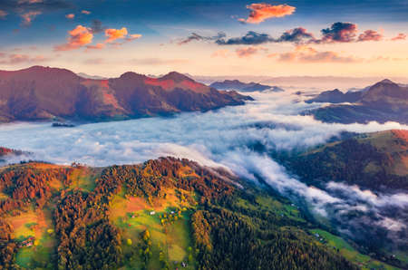 Spectacular colors sunrise on Carpathian mountains. Fog spreads on the valley of Snidavka village, Ukraine, Europe. Majestic landscape of mountain hills glowing by sunlight. Beauty of nature concept background.の写真素材