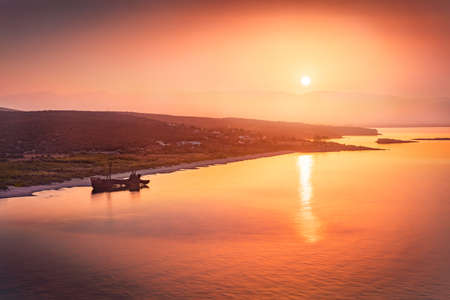 Red sunrise on Valtaki beach with Dimitrios Shipwreck. Colorful morning scene of Peloponnese peninsula, Greece, Europe. Amazing summer seascape of Mediterranean sea.の写真素材