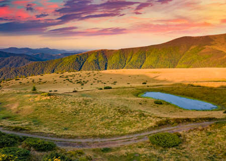beautiful autumn scenery. Colorful morning view of Carpathian mountains witj small lake and old...