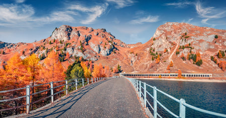 Empty walkway on dam on Fedaia lake. Sunny autumn view of the Dolomite Alps. Adorable morning scene of Italy, Europe. Travel concept background.の写真素材