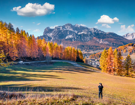 Tourist takes picture of outskirts of Cortina d'Ampezzo town. Amazing autumn view of the Dolomite Alps. Stunning outdoor scene of Italy, Europe. Travel concept background.の写真素材