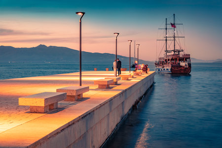 Wooden sailboat on the shore of Saranda port. Superb spring sunset on Ionian sea. Illuminated evening scene of Albania, Euroepe. Travel concept background.の写真素材