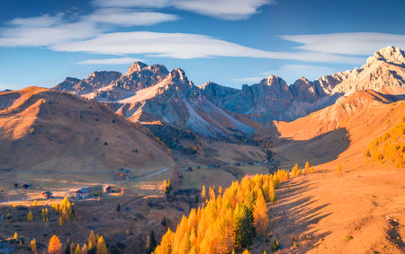 Unbelievable autumn scene of Fuchiade valley. Spectacular evening view of Dolomite Alps, Italy, Europe. View from flying drone of golden larch trees forest. Beauty of nature concept background.の写真素材