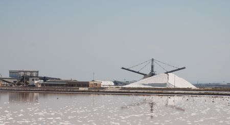 The exterior of a salt factory showing a hill of salt and various equipment used in the production process の写真素材