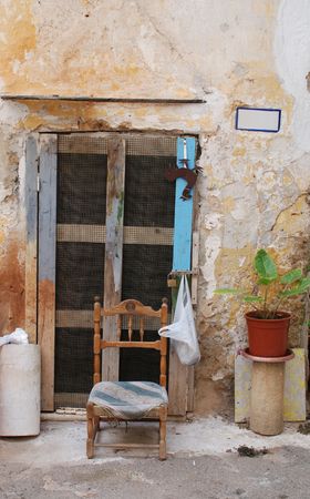 An old door in Gallipoli, Italy with a small chair outside it の写真素材